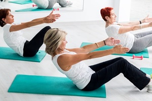 Drei Frauen von der Seite auf dem Bodenin Gymnastikpositionauf Gymnastikmatten