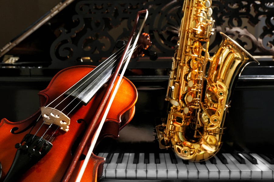 Cello lehnt an Klavierflügel. Auf den Klaviertasten steht ein Saxophon