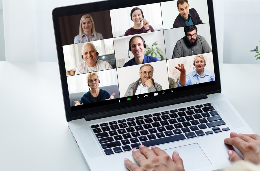 Laptop, auf dessen Display mehrere Menschen in einer Video-Konferenz zu sehen sind