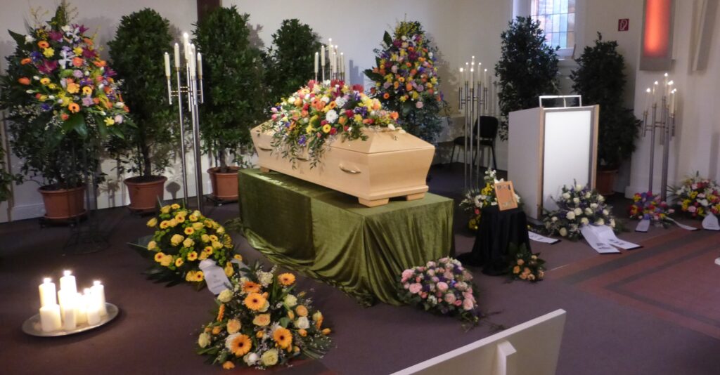 Sarg mit Blumenschmuck in einer Trauerhalle